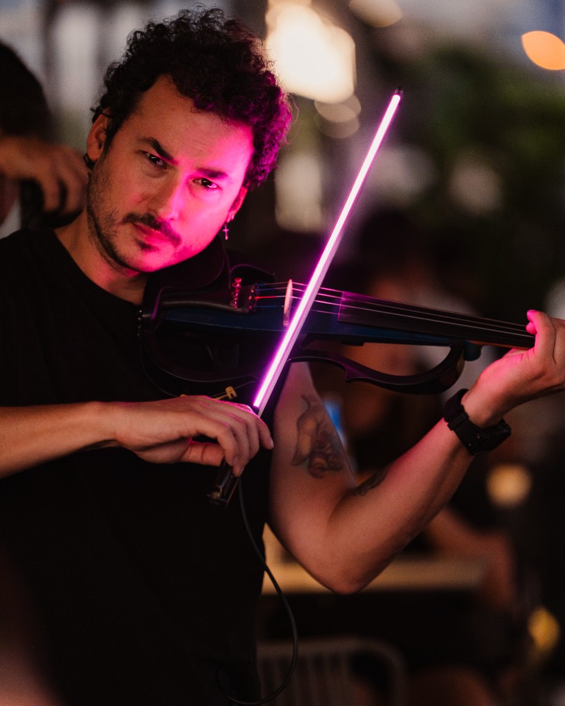 Neon-lit violinist performing at night, Central Beach Split